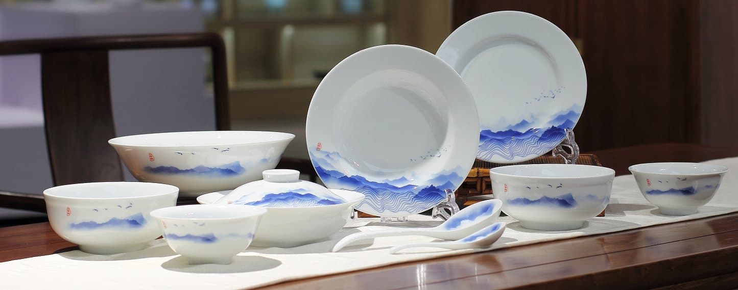 The Mountain Stream banquet service — hand-painted shan-shui porcelain on a dark wood table